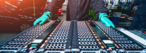 A worker with gloves observing a circuit board in a shop.